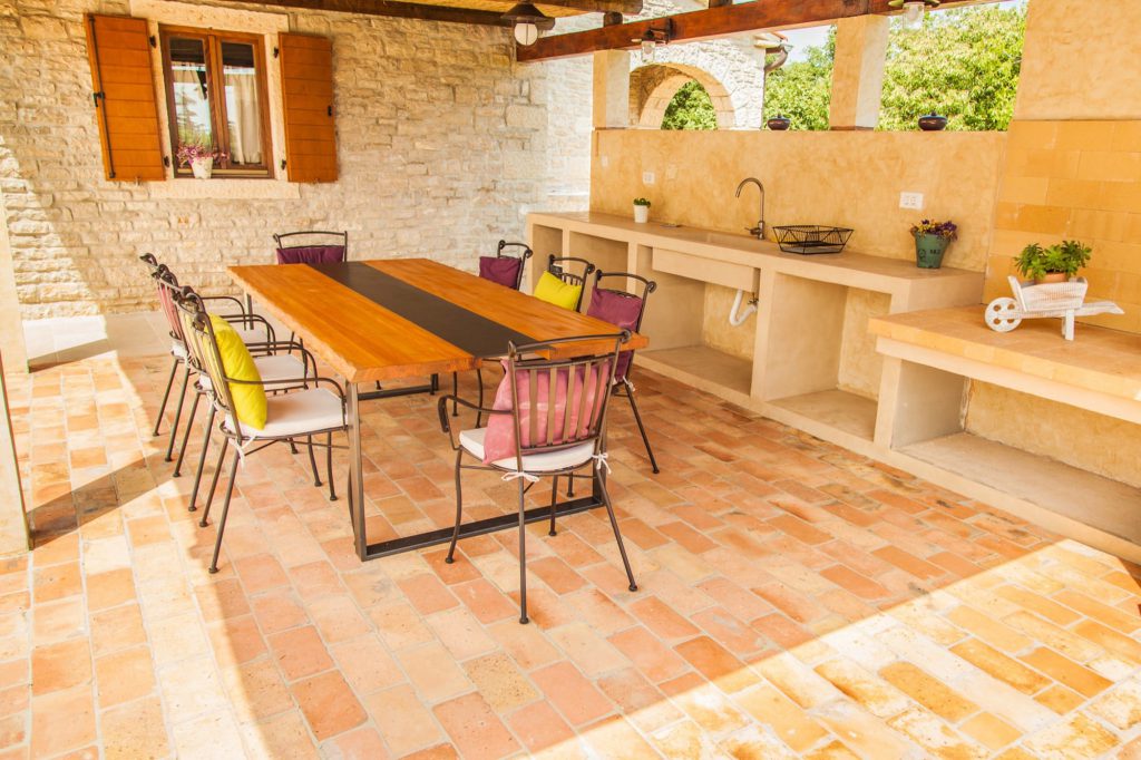 Im Außenbereich der Villa befindet sich eine überdachte, rustikale Außenküche. Hier kann gekocht und gegrillt werden.