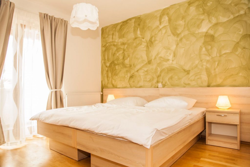 Das große Schlafzimmer beitzt einen kleinen eigenen Balkon und hat eine oliventonfarbene Wand.
