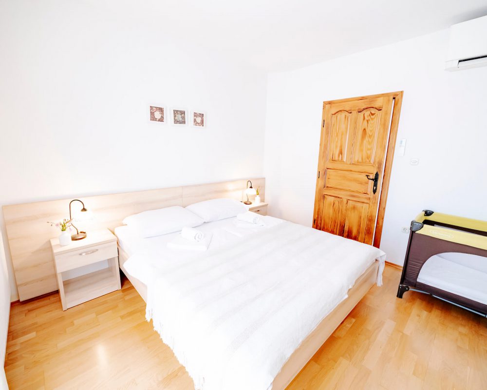 Das gemütliche Schlafzimmer, der Villa Alma, hat ein komfortables Doppelbett mit zwei Nachttischen, zwei Tischlampen sowie ein Babybett..
