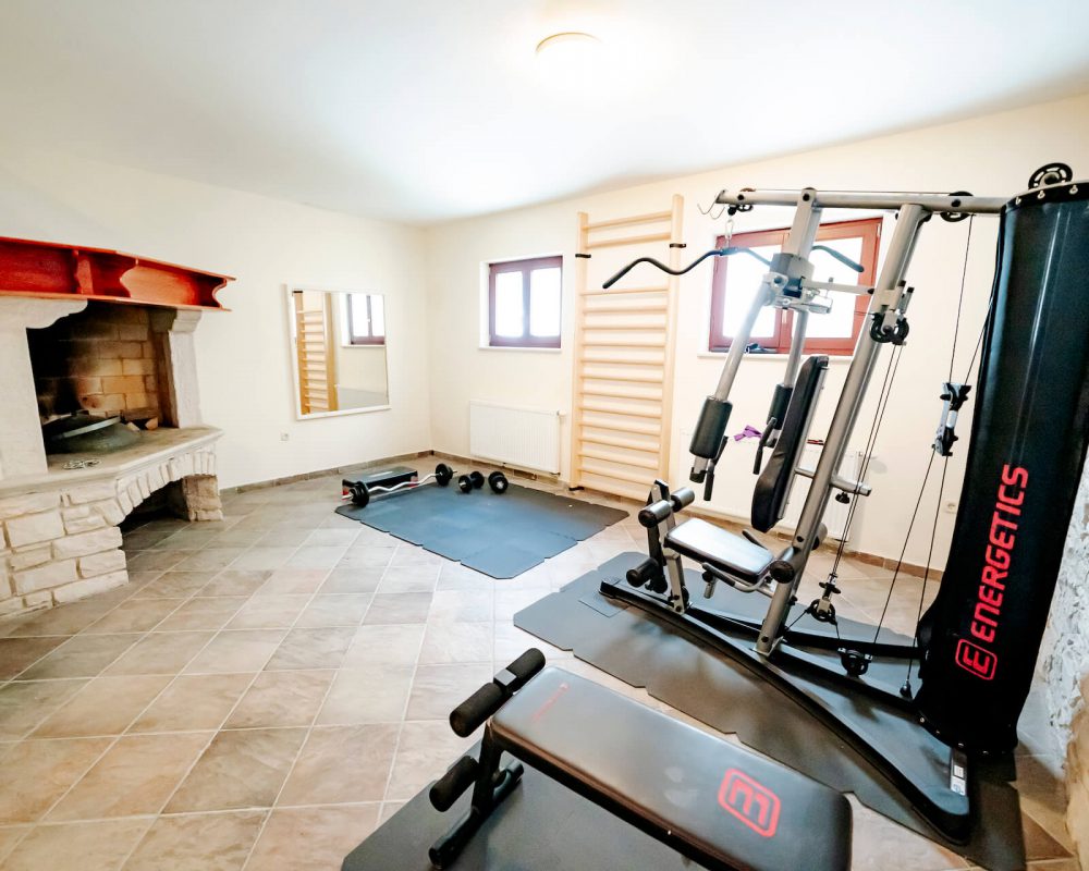 Der Fitnessraum der Villa Alma hat verschiedene Fitnessgeräte wie zum Beispiel Hanteln, eine Trainingsbank, Gymnastikbälle oder auch eine Sprossenwand.