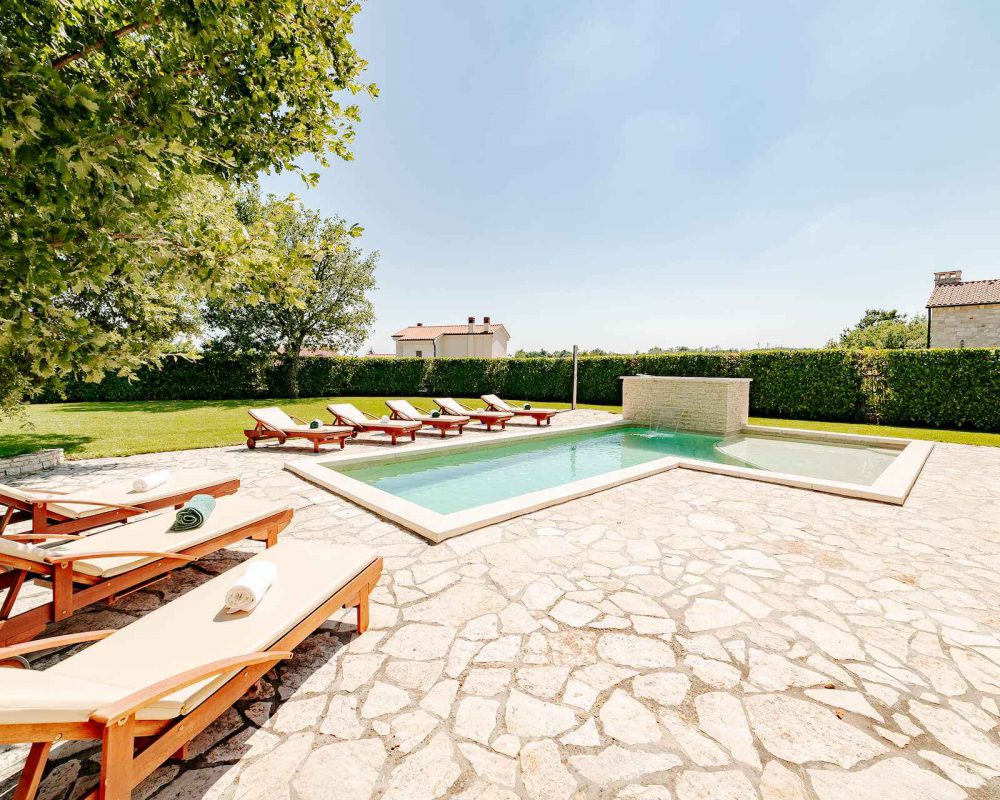 Auf der Terrasse ist ein 30m² großer Swimmingpool mit Acht schicken Sonnenliegen aus Holz.