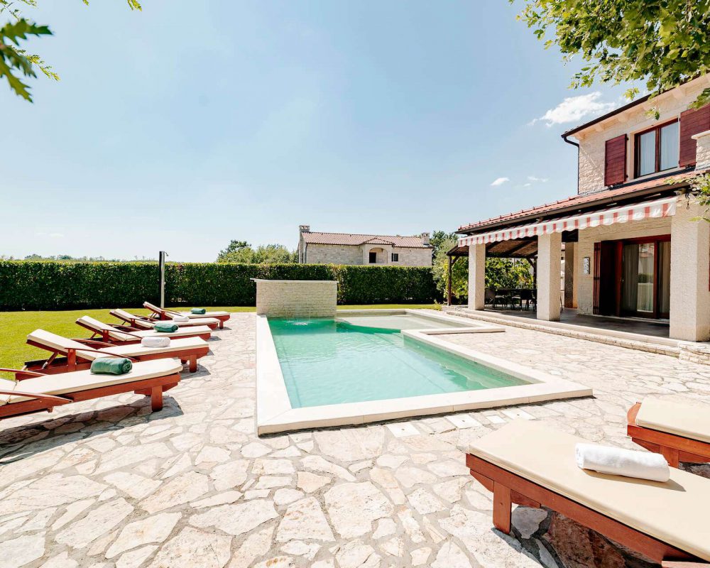Die Villa Alma, auf der Halbinsel Istrien, hat einen schicken Außenpool mit einem flachen und einem tiefen Bereich. Treppen führen in den Pool.
