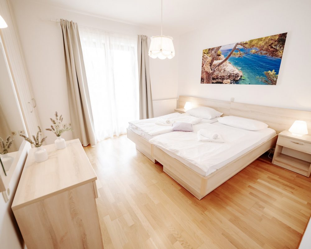 Das große Schlafzimmer beitzt einen kleinen eigenen Balkon und hat eine oliventonfarbene Wand.