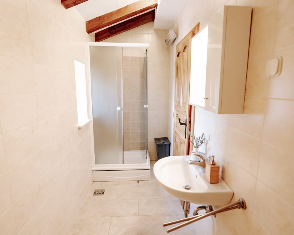 Das kleine badezimmer im Obergeschoss hat eine Dusche und einen kleinen quaratischen Badschrank mit einzelnen Fächern.