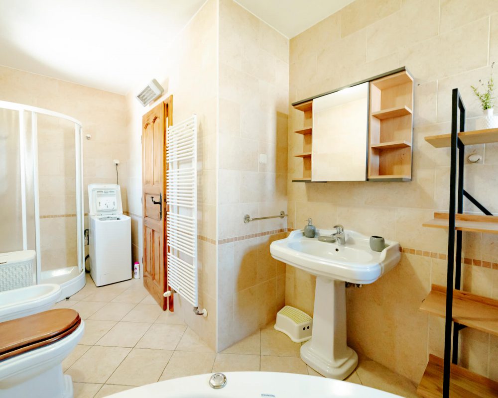 Das große Bad in der ersten Etage besteht aus einer Toilette, einer Dusche mit Schiebetüren und einer Eckbadewanne.