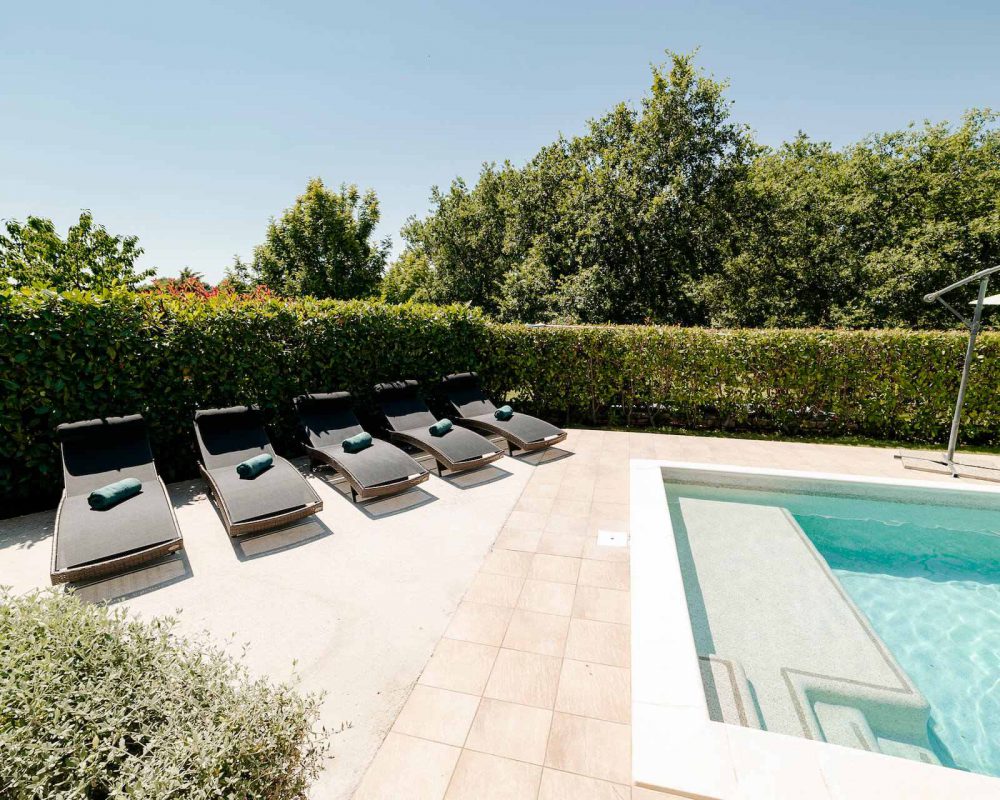 Auf der großen Terrasse der Villa Dracena stehen sechs schicke Sonnenliegen mit Blick auf den erfrischenden Swimmingpool.