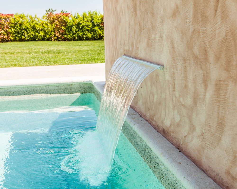 Der Swimmingpool hat einen Wasserfall, der direkt in das tiefe Becken fällt.