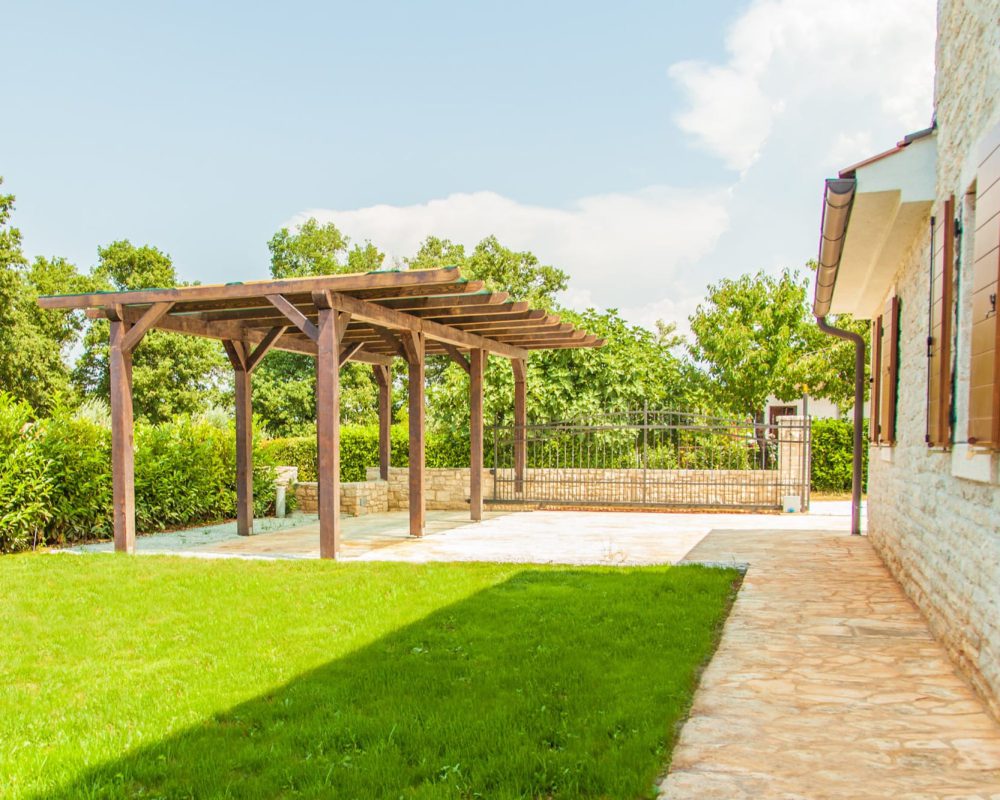 Das Carport des Ferienhauses ist luftig übredacht, damit die Fahrzeuge im Schatten stehen können.